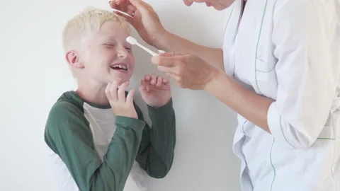 The dentist brushes the boy's sensitive teeth with a blond toothbrush Stock Footage 134671801