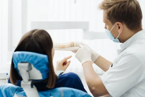 Dentist checking and selecting color of young woman's teeth Stock Photos