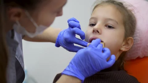 Dentist checking child's teeth, using wooden stick, close-up Stock Footage 285214731