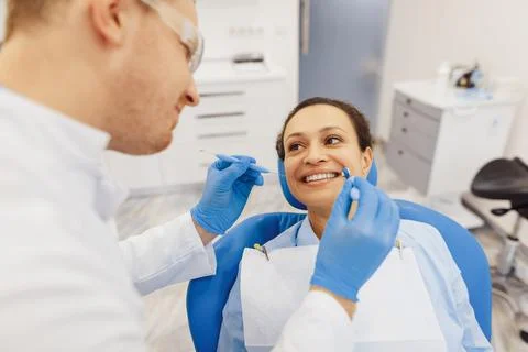 Dentist checking female client teeth with mirror Stock Photos