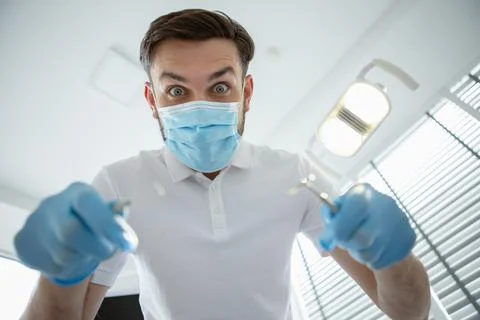 Dentist checking patient teeth with mirror in modern clinic Stock Photos