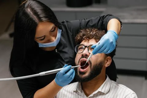 Dentist checking patient's teeth during oral examination Stock Photos