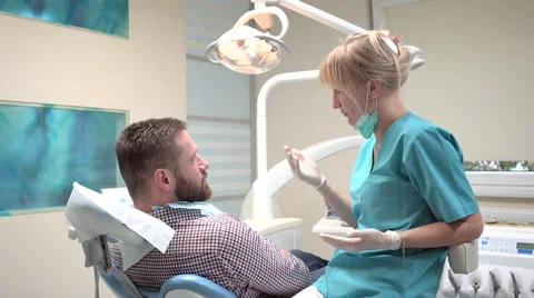 Dentist checking up teeth of patient and talking with him. Slider shot, right. 動画素材 68525094