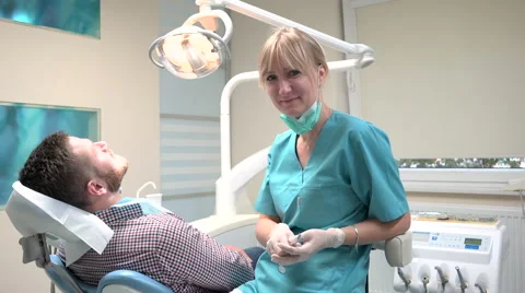 Dentist checking up teeth of patient, looks to the camera. Slider shot, right. Vidéo 68525579