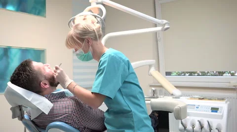 Dentist checking up teeth of patient, looks to the camera. Slider shot, left. 库存影片 68525650