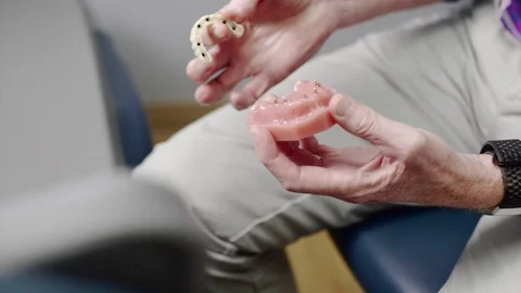 Dentist demonstrating how dentures can be mounted with implants Stock Footage 113750143