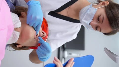 Dentist demonstrating proper flossing technique to patient in dental office Stock Footage 258689937