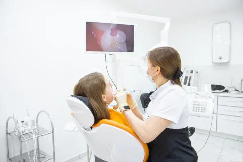 Dentist diagnoses teeth of patient using intraoral camera in treatment room Stock Photos