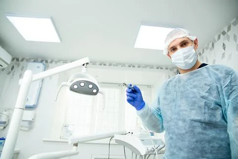 The dentist directs the lighting device at the client Stock Photos