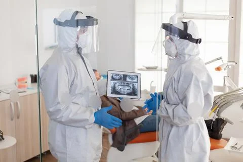 Dentist doctors in overall using tablet explaining dental x ray Stock Photos