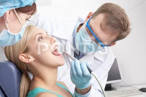 A dentist drilling a young woman s teeth Stock Photos