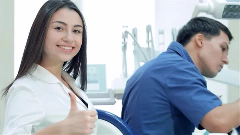 Dentist drills teeth while smiling assistant gives thumbs up Stock Footage 311933631