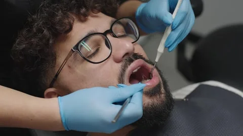 Dentist examines patient teeth while providing detailed dental treatment Stock Footage 331515381