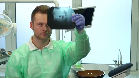 Dentist examines x-ray under bright light Stock Footage 311981212