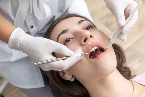 Dentist examining patient teeth with dental mirror during dental check up Stock Photos