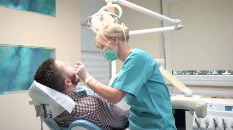 Dentist examining patient's teeth, explains him procedure. 動画素材 68525748