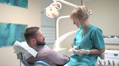 Dentist examining patient's teeth explains him procedure. Slider shot, right. Stock Footage 68525803