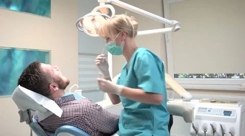 Dentist examining patient's teeth explains him procedure. Slider shot, left. 库存影片 68525932