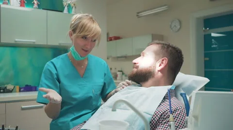 Dentist examining patient's teeth, explains him procedure. 库存影片 68715465