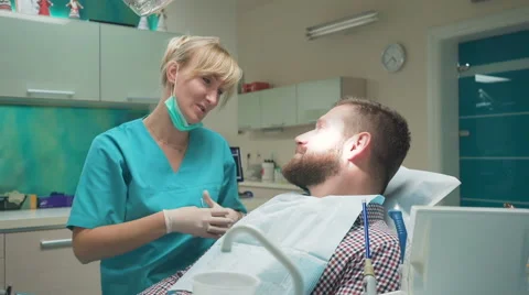 Dentist examining patient's teeth, explains him procedure. Slider shot, right. 库存影片 68715535
