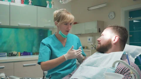 Dentist examining patient's teeth, explains him procedure. Slider shot, left. 库存影片 68715586
