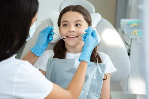 Dentist examining teeth of smiling client in dental chair Stock Photos