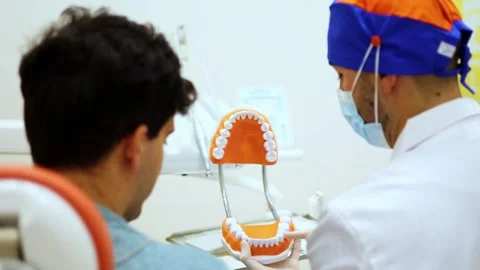 Dentist explaining brushing technique to patient using dental mold Stock Footage 295628111
