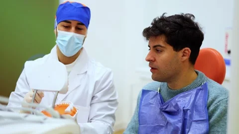 Dentist explaining dental treatment using teeth model to patient Stock Footage 295628103