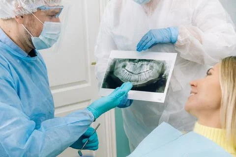 Dentist explaining the details of the X-ray to his patient in the office Stock Photos