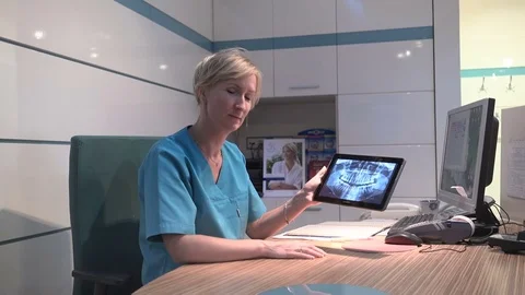 Dentist explaining procedure on x-ray, smiling to camera. Steadicam shot. Vídeo Stock 70307187