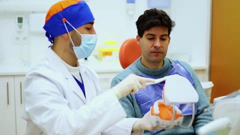 Dentist explaining teeth hygiene using anatomical model Stock Footage 295627641
