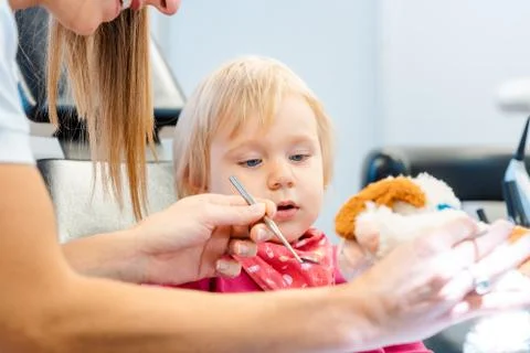 Dentist explaining treatment to a child using a plush toy Stock Photos