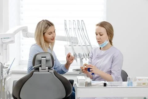 Dentist explaining treatment to patient using dental mold in clinic 库存照片