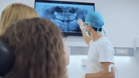 Dentist Explaining X-ray Results to Patients in Clinic Foto stock