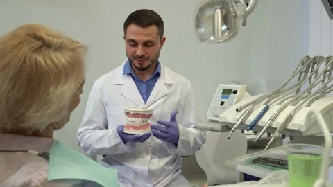 Dentist explains dental layout to his female client with a model Stock-Footage 311945955