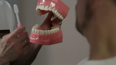 Dentist explains the man how to properly brush their teeth Stock Footage 61852394