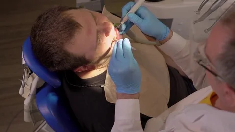 Dentist in Glasses Pulls The Saliva Ejector From the Oral Cavity of the Patient Stock Footage 76722360