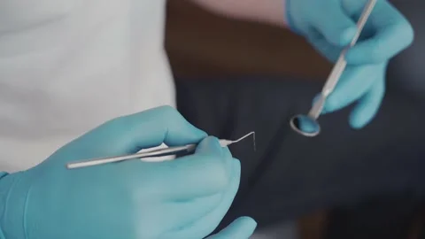 The dentist holds tools and prepares for the patient's treatment.  Vídeo Stock 196891716