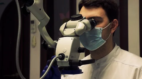 Dentist looks through a modern microscope during a procedure Video stock 128735611
