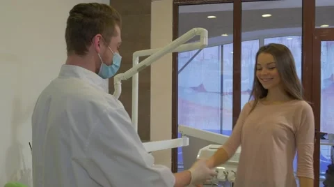 Dentist Meets a Client Shakes a Hand Woman Patient Lies Down on a Chair Doctor Stock Footage 60980234