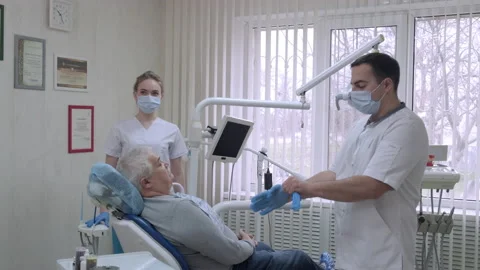 Dentist with nurse in protective masks preparing to examine a patient in dental Stock Footage 170660864