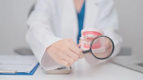 Dentist with Orthodontic tooth model and bracket or brace. Clean and Scrape.. Stock Footage 337919686