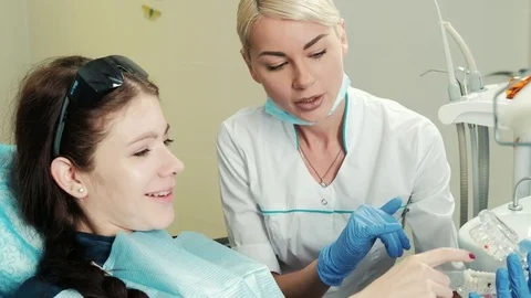 Dentist with patient discuss types of future crowns using artificial jaw. Stock Footage 73149236
