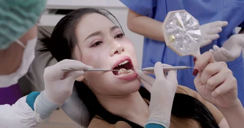 Dentist performing tartar removal using dental scaler on Asian adult woman Stock Footage 318942910