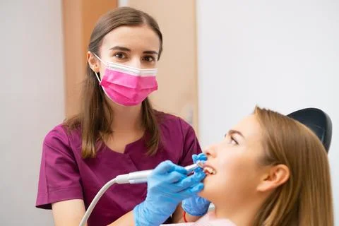 A dentist is performing a teeth grinding procedure on a lovely woman to enhance Stock Photos