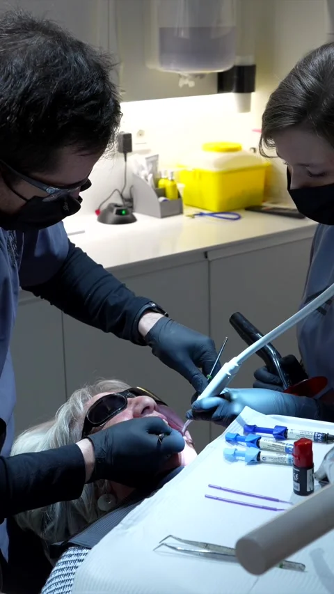 Dentist performing teeth whitening procedure on senior patient Stock Footage 306061212