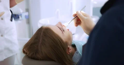 The dentist performs an examination using a dental mirror a woman Stock Footage 165450675