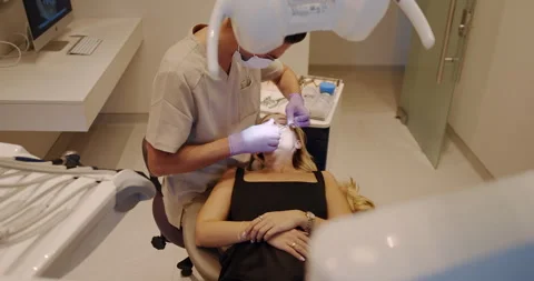 A dentist performs an oral procedure in a modern clinic to ensure patient Stock Footage 318280035