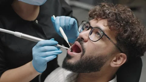 Dentist performs teeth cleaning on patient in clinic using tools and techniques Stock Footage 324980415