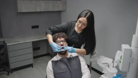 Dentist performs treatment on a patient inside a modern dental clinic Video stock 320877765